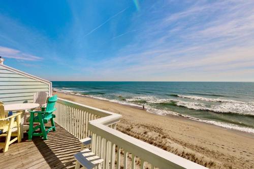 a deck with a table and chairs on the beach at Sea Forever in Kure Beach