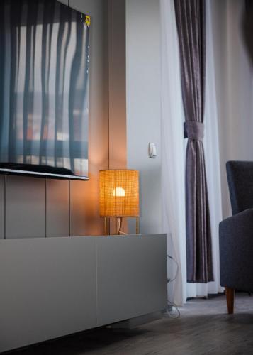 a living room with a tv and a lamp on a cabinet at Nil's Apartments in Peje