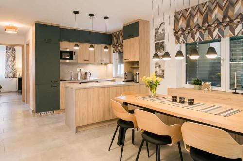 a kitchen with green cabinets and a large wooden table at EMMY Ház in Badacsonytomaj
