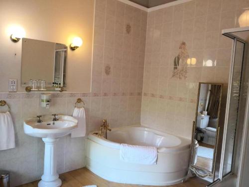 a bathroom with a bath tub and a sink at OYO Dunmar House Hotel in Alloa