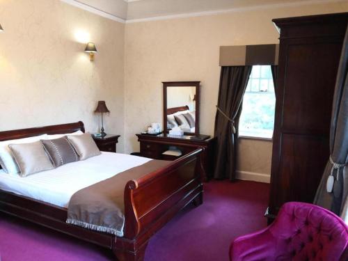 a bedroom with a bed and a mirror and a chair at OYO Dunmar House Hotel in Alloa