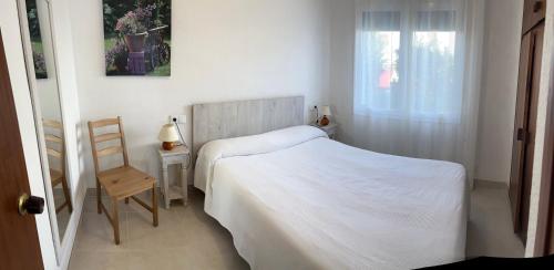 a bedroom with a bed and a chair and a window at Apartamentos Miradores in Miami Platja