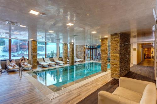 a pool in a hotel room with a woman sitting on a couch at Апартаменти Форест Нук - ФАЗА 1 in Pamporovo