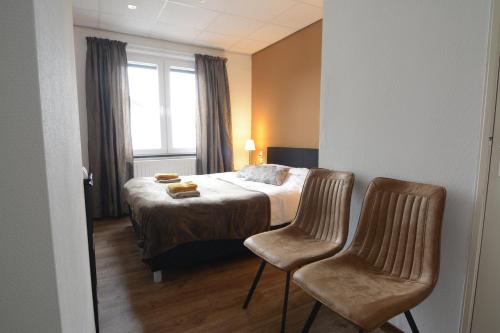 une chambre d'hôtel avec un lit et deux chaises dans l'établissement Bed & Breakfast Hotel Het Gerendal, à Schin op Geul