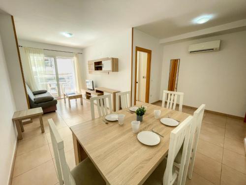uma sala de jantar e sala de estar com uma mesa de madeira e cadeiras em Apartamentos Neptuno 3000 em Alcossebre