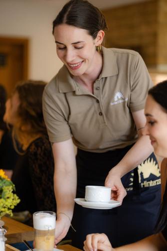 a woman is holding a cup on a plate at Hotel Sonne Garni in Hinterzarten