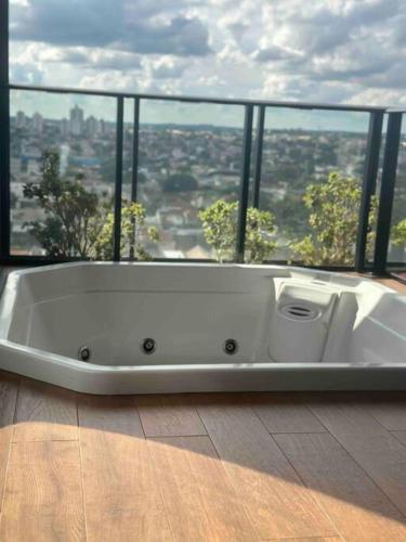 a white bath tub in a room with a large window at Loft moderno e Hi- tech Vertigo in Campo Grande