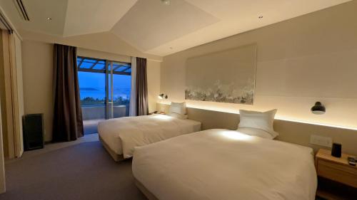 a hotel room with two beds and a window at Hotel Anaga in Minamiawaji