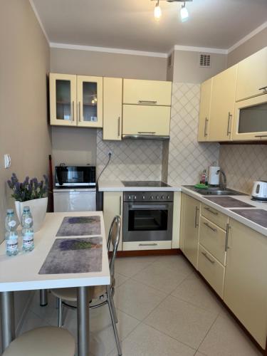 a kitchen with yellow cabinets and a table with chairs at Apartament Beauty in Ełk