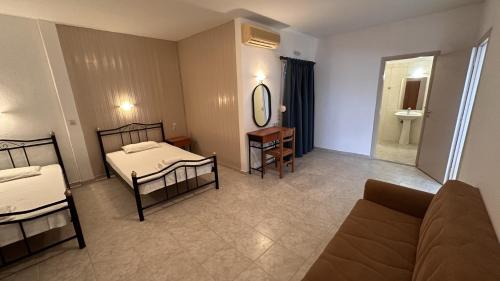 a room with two beds and a couch and a mirror at Sfinias Apartments in Kali Limenes