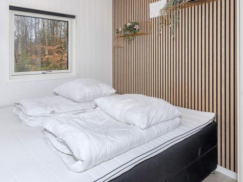 1 cama con sábanas blancas y almohadas en una habitación en Holiday home Aars III, en Års