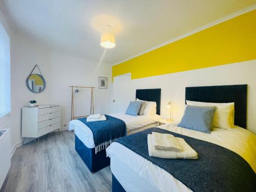 - 2 lits dans une chambre de couleur jaune et blanche dans l'établissement Stunning 2-Bed Apartment in Greenock - Sleeps 6, à Greenock