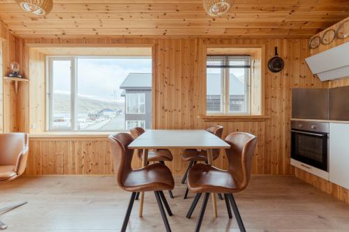 a kitchen with a table and leather chairs in a room at Lítlastova - A Charming Boathouse Getaway in Hvalvík
