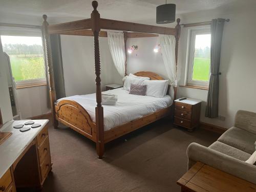 a bedroom with a four poster bed and two windows at Hazeldene Hotel in Gretna Green