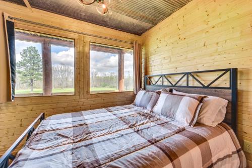 a bed in a room with wooden walls and windows at Waterfront Marksville Studio with Dock! in Marksville