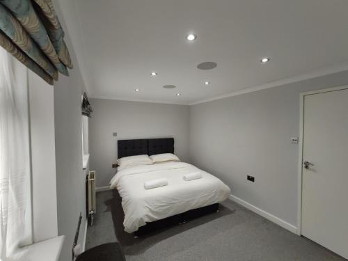 a bedroom with a bed in a white room at Elegant 3-Bedroom Home, sleeps up to 5 guest. in South Ockendon