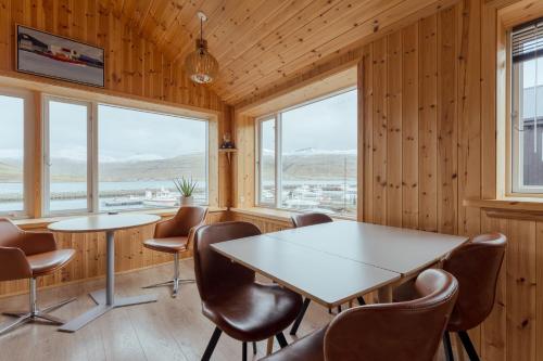 a meeting room with a table and chairs and windows at Lítlastova - A Charming Boathouse Getaway in Hvalvík