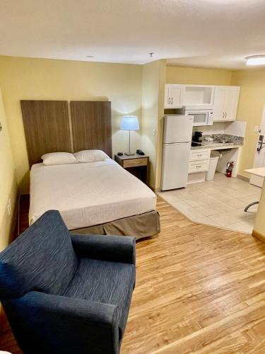 a bedroom with a bed and a couch and a kitchen at Suburban Studios Fort Myers Cape Coral in Fort Myers