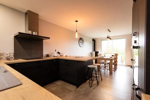 a kitchen with black cabinets and a kitchen island with a table at Maison au calme * parking privé * wifi in Villemandeur