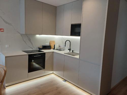 uma cozinha com armários brancos, um lavatório e um fogão em OPORTO Suites em Moreira