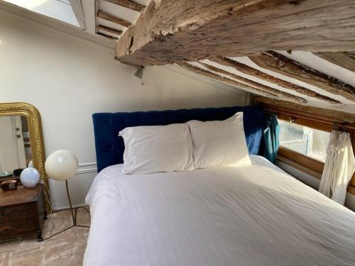 a bedroom with a bed with a blue headboard and a mirror at Central Duplex with Panoramic Views over Paris in Paris