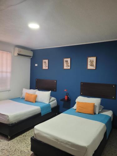 2 Betten in einem Zimmer mit blauer Wand in der Unterkunft Costana - Hostal in Cartagena de Indias