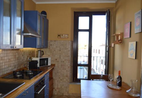 cocina con armarios azules y encimera con ventana en Clementina sunset apartment, en Fiumicino