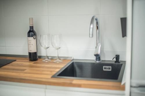 a bottle of wine and two wine glasses on a kitchen counter at Ático en Calella a 7 minutos de la playa in Calella