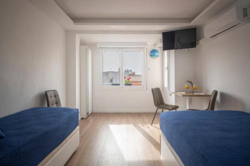 a room with two beds and a table and a window at Ático en Calella a 7 minutos de la playa in Calella