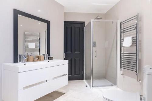 a bathroom with a sink and a shower and a mirror at Bright and Spacious - 2 Bed Flat w/ Jacuzzi in Crystal Palace