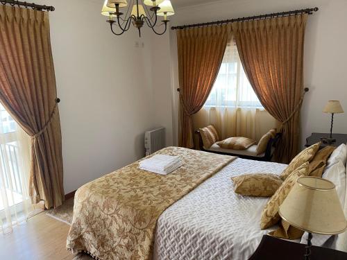 een slaapkamer met een bed, een stoel en ramen bij Casa dos Pexins in Nazaré