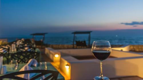 a glass of wine sitting on a table near the ocean at Le Bleu Hotel & Resort Kusadasi in Kusadası