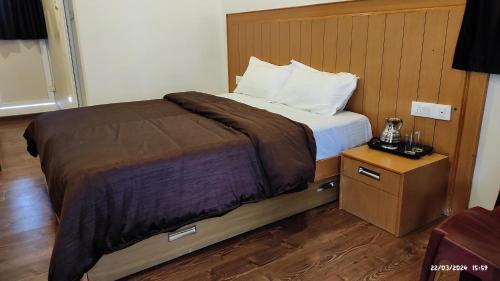 a bedroom with a bed with a wooden headboard at Magizham Homestay in Kodaikānāl