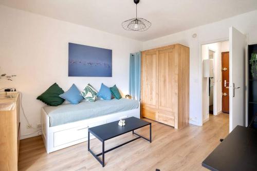 Un dormitorio con una cama con almohadas azules y una mesa. en L'Amarante, T1 avec Terrasse, Beaux Arts, en Montpellier