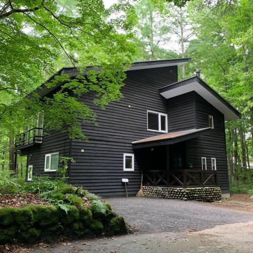 a black house in the middle of a forest at Kitakaruizawa Morino Bessou NO1 in Kita-karuizawa