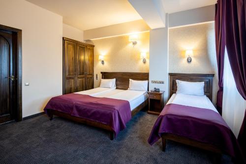 2 camas en una habitación de hotel con sábanas moradas en Pension Korona, en Sibiu