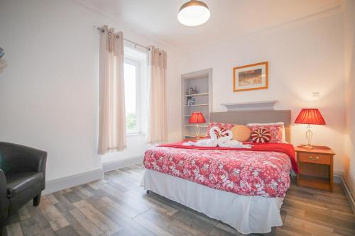 a bedroom with a bed with a redspread and a window at Telford Rd 5 Bedroom House Inverness in Inverness