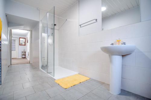 ein weißes Bad mit einem Waschbecken und einer Dusche in der Unterkunft Novar 4 Bedroom House Alness in Inverness