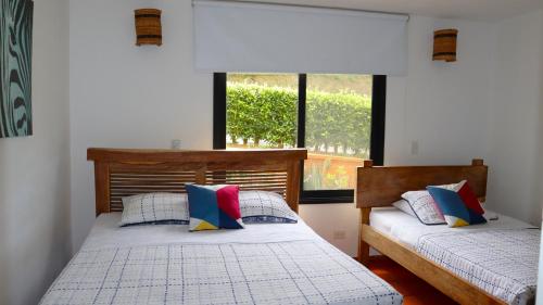 two beds in a room with a window at Finca PANACA Jagüey 12 VIP Group - Villas for Rent in in Quimbaya