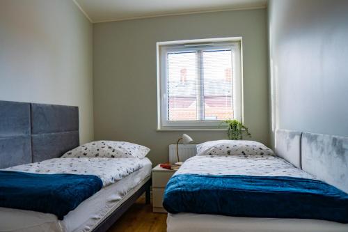 two beds in a room with a window at Apartament Nr 2 Zaułek Portowy in Ustka