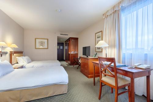 a hotel room with two beds and a desk at Evergreen Laurel Hotel in Levallois-Perret