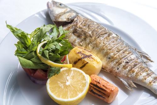 a plate of fish and vegetables on a white plate at Le Bleu Hotel & Resort Kusadasi in Kusadası