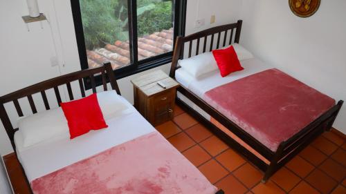 two beds with red pillows in a room with a window at Finca PANACA Jagüey 12 VIP Group - Villas for Rent in in Quimbaya