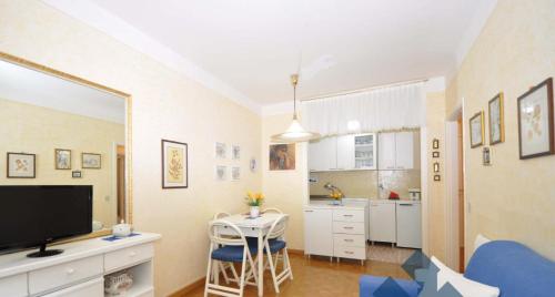 a living room with a tv and a table and a kitchen at A casa di Ale - Foppolo in Foppolo