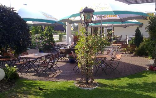 an outdoor patio with tables and chairs and umbrellas at Hotel Am Wintergarten in Bocholt