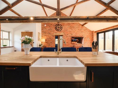 eine Küche mit einem weißen Waschbecken und einer Ziegelwand in der Unterkunft Beth's Cottage in Malton