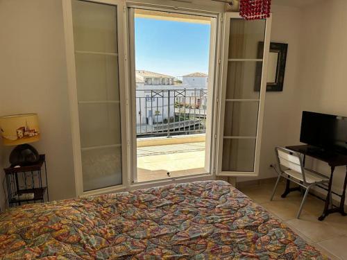 ein Schlafzimmer mit einem Bett und einem großen Fenster in der Unterkunft Marina 4 adultes 4 enfants piscine commune in Aigues-Mortes