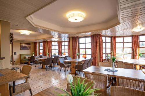 a restaurant with tables and chairs and windows at Lieblingsplatz Hotel Seedeich in Grömitz