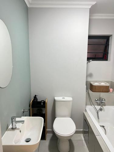 biała łazienka z toaletą i umywalką w obiekcie Jabulani junction w mieście Soweto
