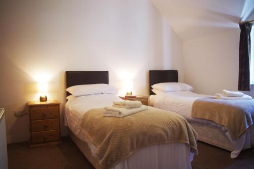 a bedroom with two beds with towels on them at Ty Ceiniog New Quay in Cross Inn
